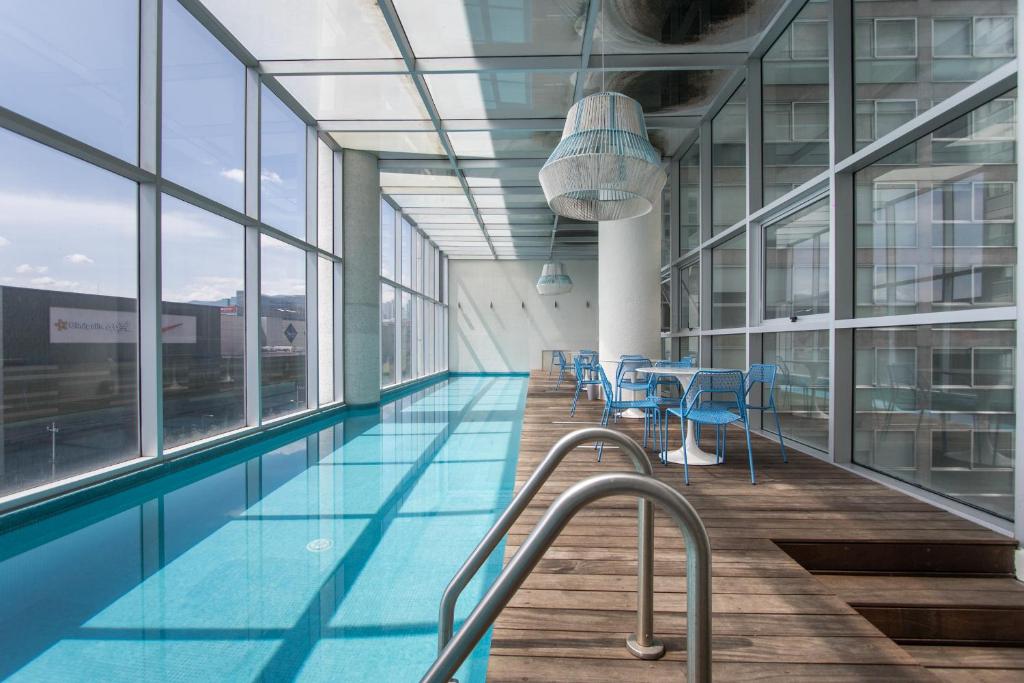 a swimming pool in a building with windows at Live Santa Fe in Mexico City