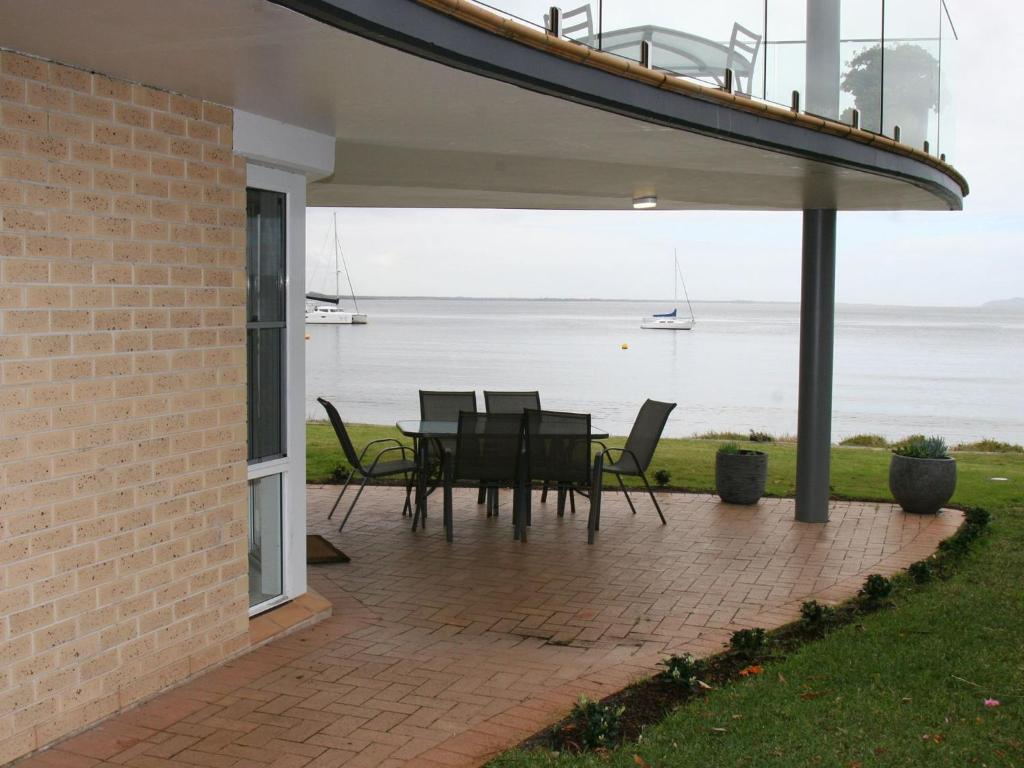 a patio with a table and chairs and a view of the water at The Clippers 1 fabulous waterfront unit in Salamander Bay