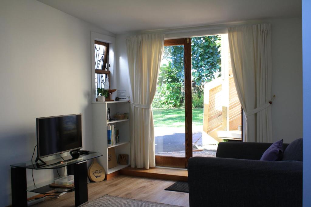 a living room with a television and a sliding glass door at Aquavilla Studio in Plimmerton