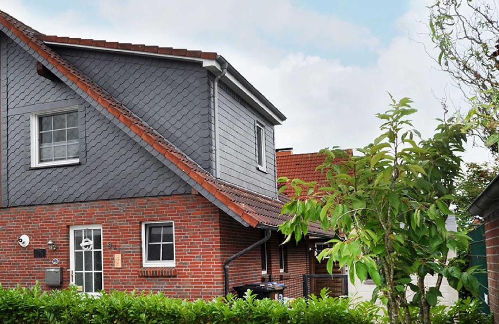 una casa de ladrillo rojo con techo negro en Ferienhaus Alana, en Hooksiel