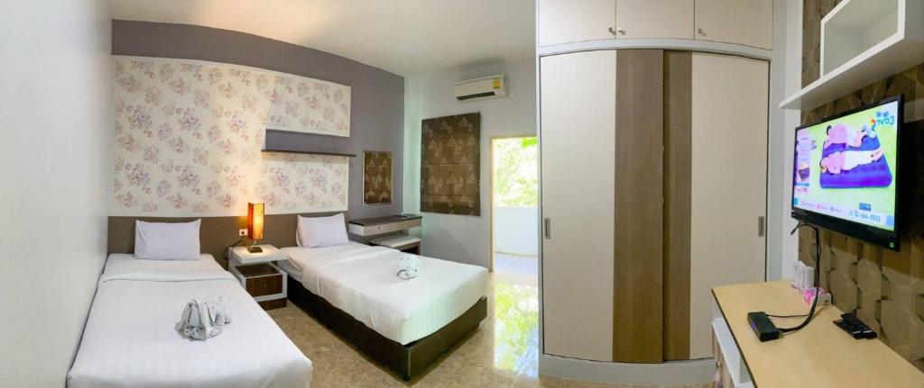 Habitación de hotel con 2 camas y TV de pantalla plana. en Cupid Hotel, en Ban Thung Yao