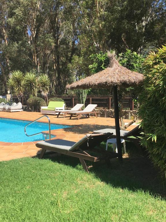 a pool with a straw umbrella and lounge chairs and a swimming pool at Molino El Mastral in Tarifa