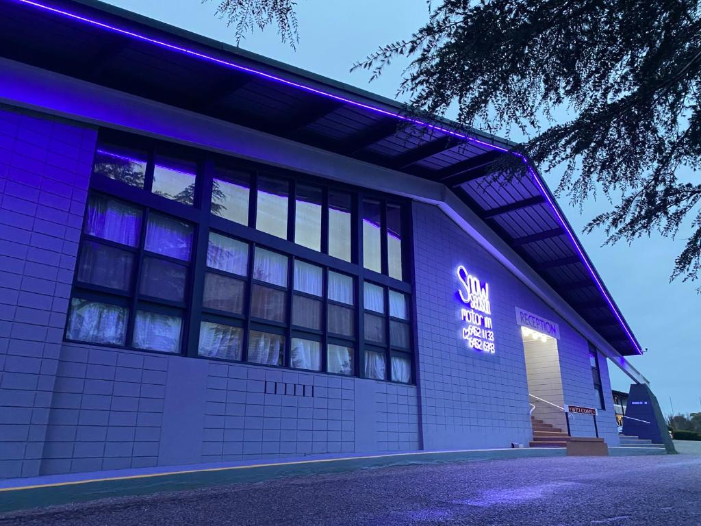 un bâtiment avec un panneau de néon violet sur lui dans l'établissement Snow Season Motor Inn, à Cooma