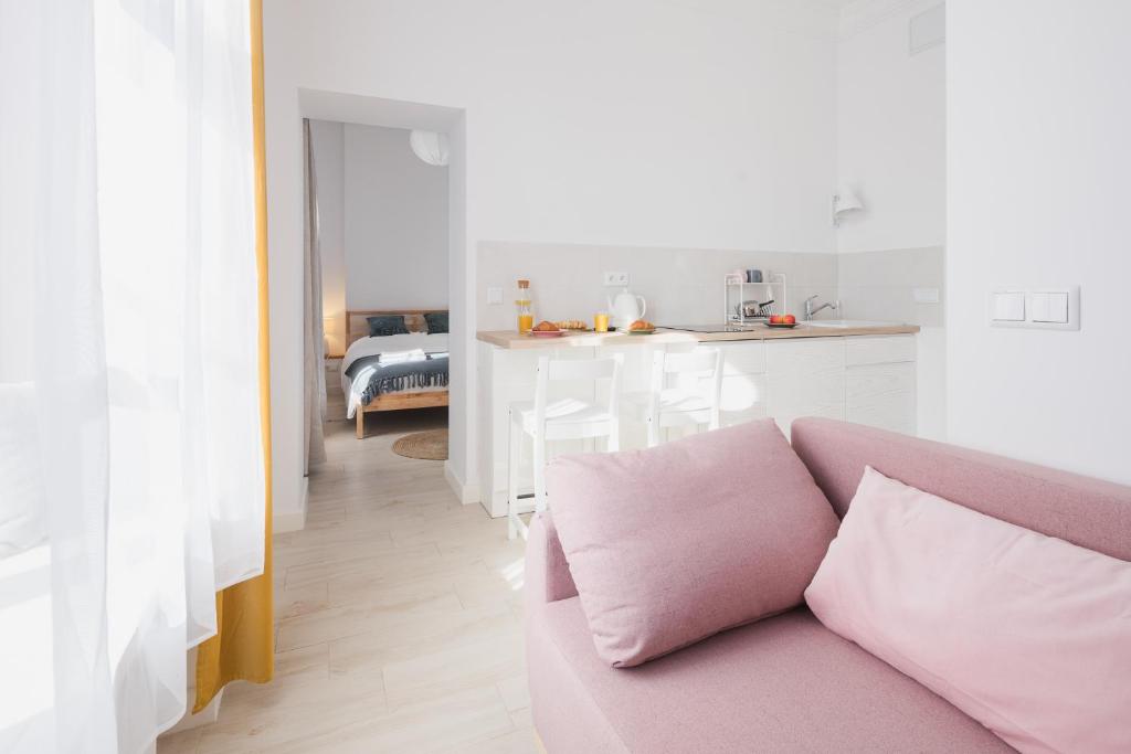 a living room with a pink couch and a kitchen at Piotrkowska Welcome Apartments in Łódź