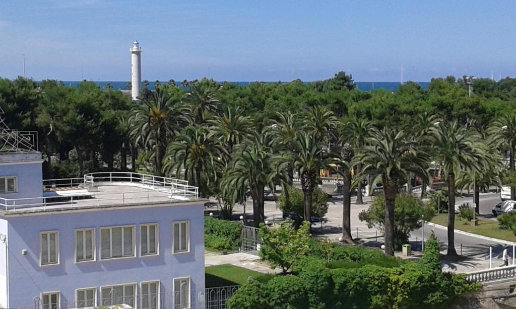 biały dom z palmami i latarnią morską w obiekcie Hotel La Palazzina w mieście San Benedetto del Tronto