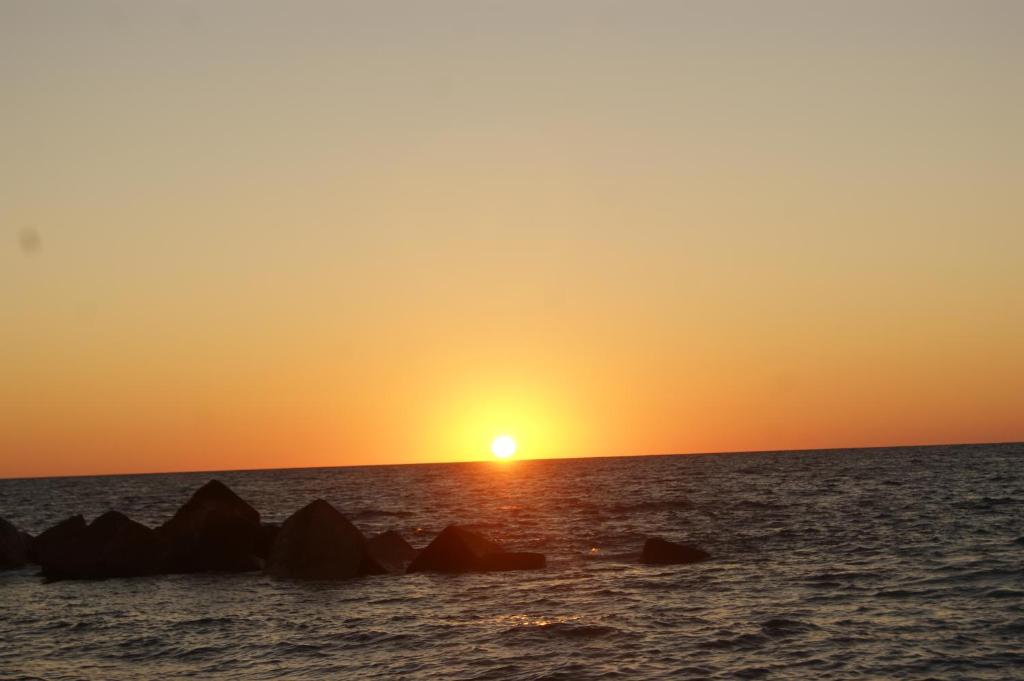 a sunset over the ocean with rocks in the water at IKEA in Piraino