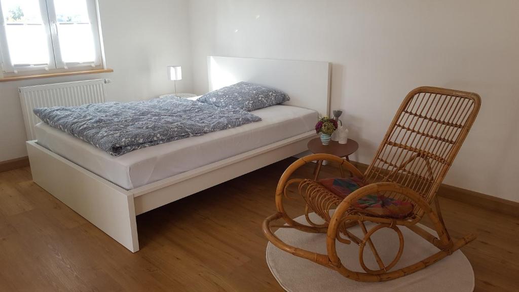 een slaapkamer met een bed en een schommelstoel bij Ferienwohnung Zellner in Deggendorf