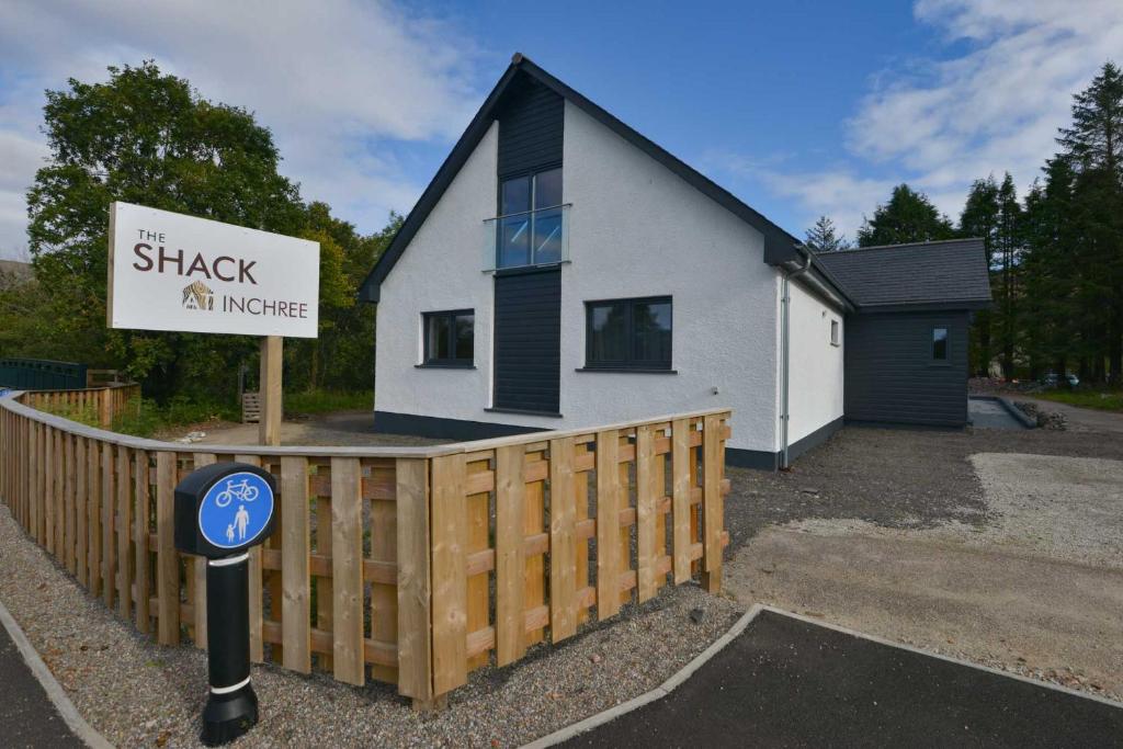 una pequeña casa blanca con un cartel delante en The Shack & Pods at Inchree en Corran