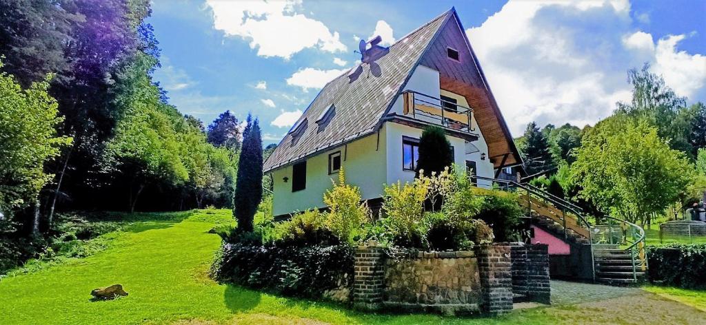 a house on a green field with trees and a sky at Chata Mraveneček in Lipova Lazne