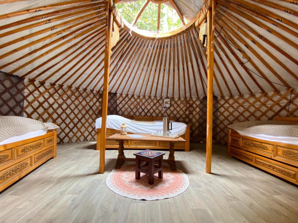 una habitación con 2 camas y una mesa en una yurta en Les Yourtes Du Béarn - Domaine des deux clos en Pontiacq-Viellepinte