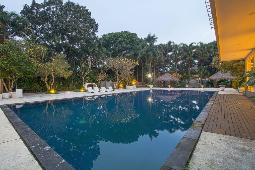 a swimming pool with chairs and trees in the background at Sheo Resort Hotel in Bandung