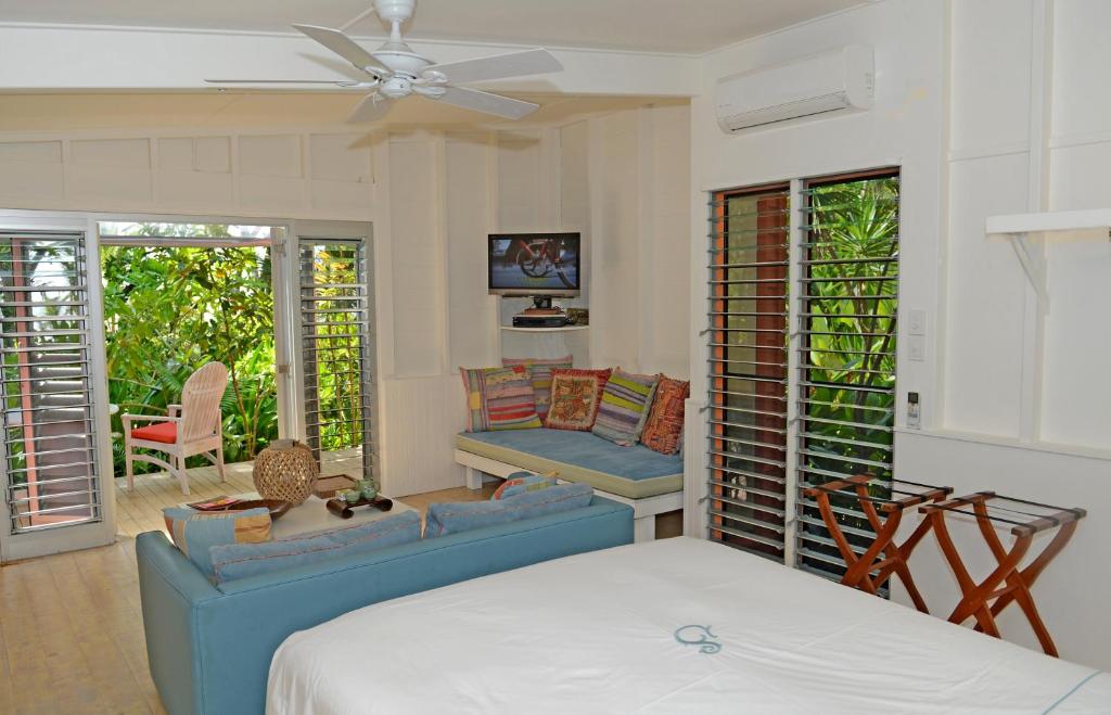 a bedroom with a bed and a couch and chairs at Sejala Beach Huts in Mission Beach