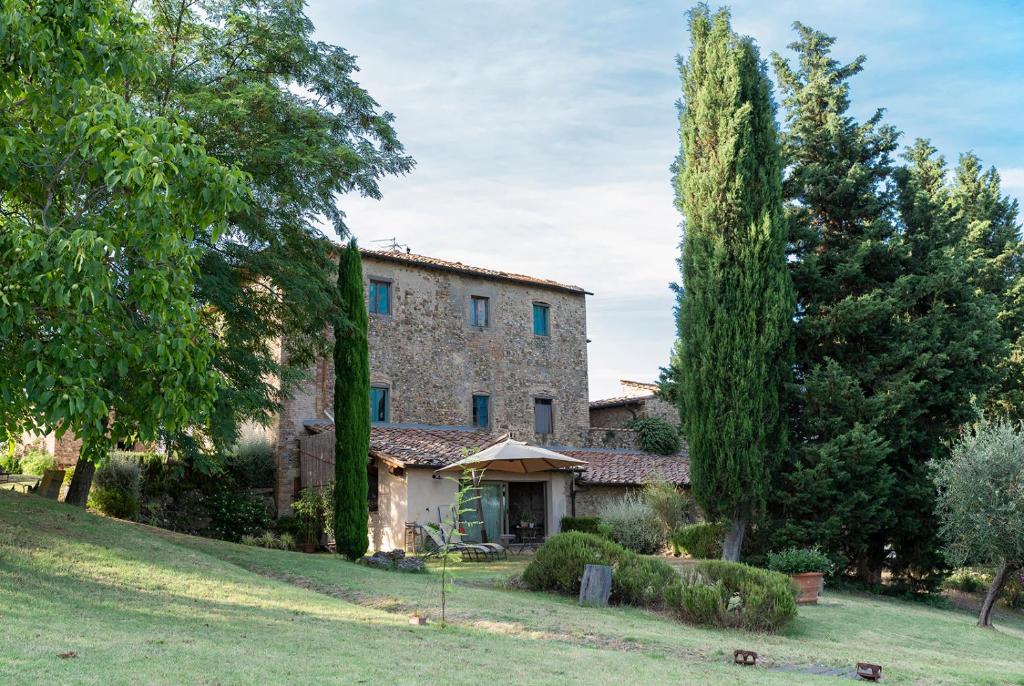 a large stone house with trees in the yard at Podere Paglieri Apartments in Montespertoli