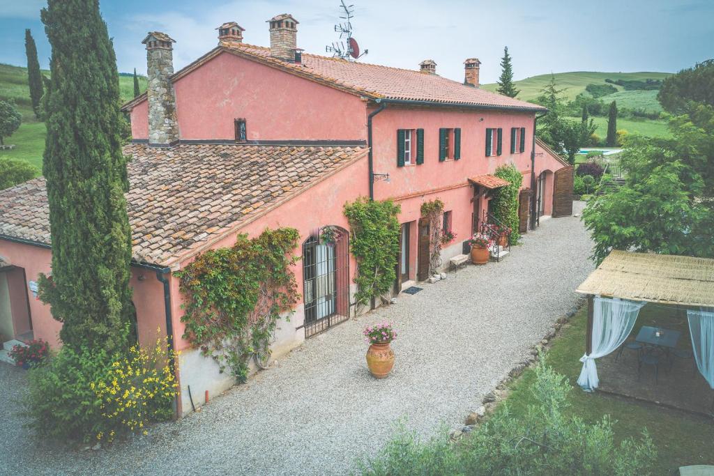 una gran casa rosa con un camino delante de ella en Villa d'Orcia - Homelike Villas en Castiglione dʼOrcia