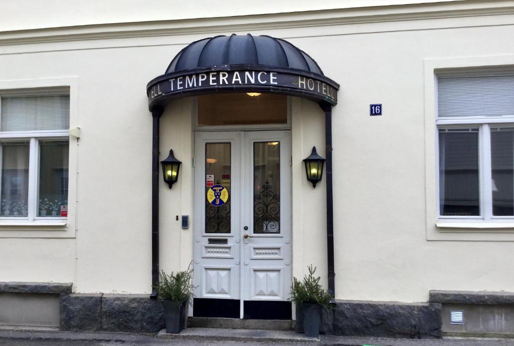a white building with a sign above the door at Hotell Temperance in Hudiksvall