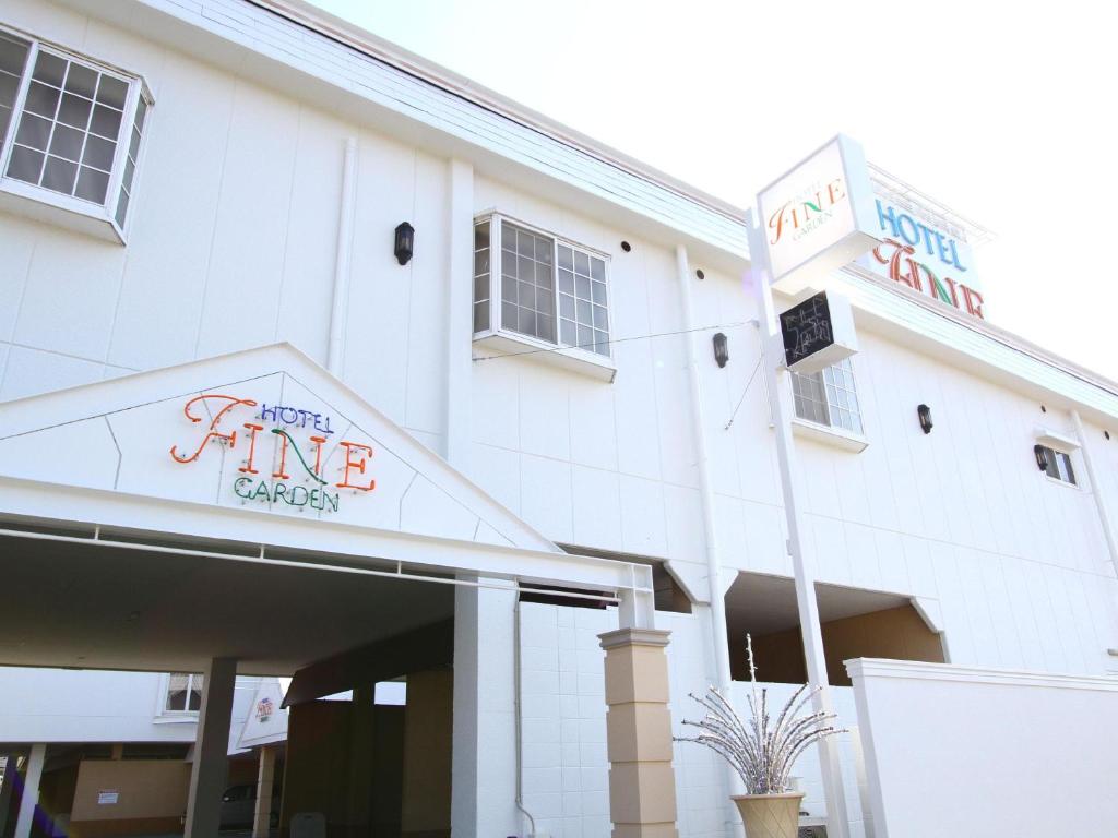 un edificio blanco con un letrero que lee el garaje del tiempo de esperanza en Hotel Fine Garden Matsuzaka III, en Matsusaka
