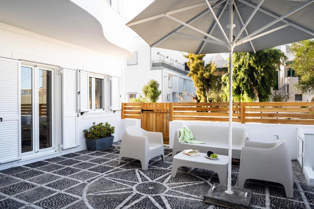 an outdoor patio with an umbrella and chairs at Thira Gold Suites in Fira