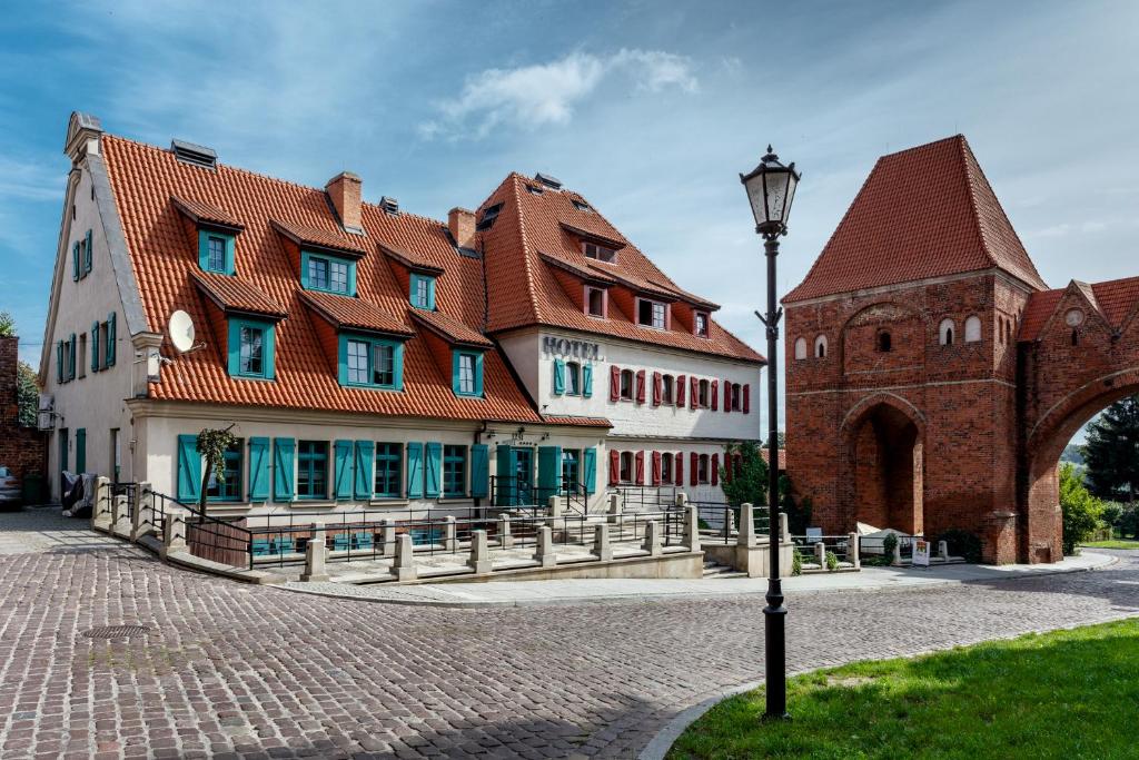 duży budynek z czerwonym dachem i światłem ulicznym w obiekcie Hotel 1231 w Toruniu