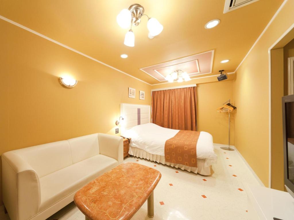 a hotel room with a bed and a couch at Hotel Fine Garden Suzuka in Suzuka