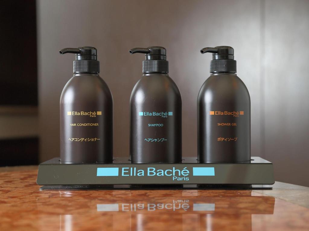 a set of three shampoo bottles sitting on a stand at Hotel Fine Garden Suzuka in Suzuka