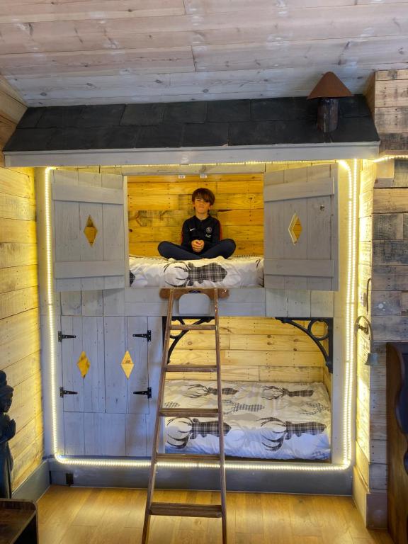 a boy sitting in a bunk bed in a house at Willow Court Farm Studio East & Petting Farm, 8 mins to Legoland & Windsor, 15 mins to Lapland UK in Windsor