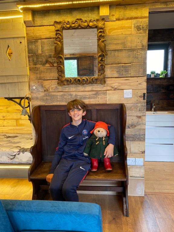 a young boy sitting on a bench with a teddy bear at Willow Court Farm Studio East & Petting Farm, 8 mins to Legoland & Windsor, 15 mins to Lapland UK in Windsor