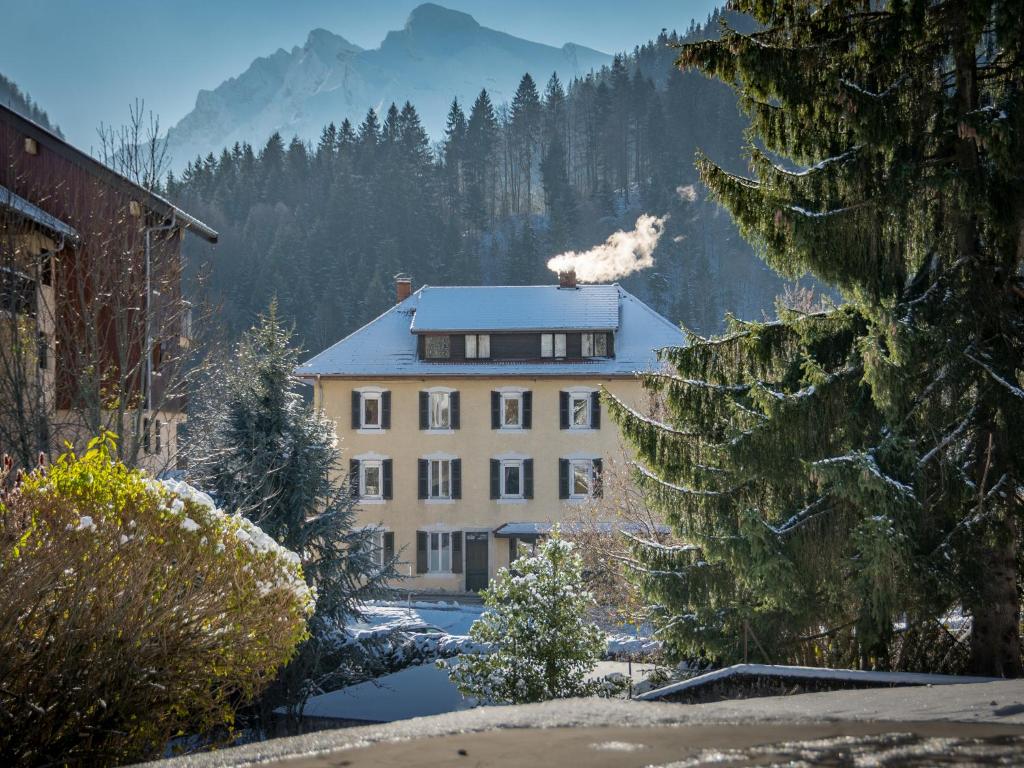 a building with a snow covered roof in the mountains at Hotel Les Aravis in Saint-Jean-de-Sixt