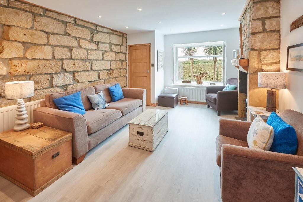 a living room with a couch and a stone wall at Host & Stay - The Cottage, Marske in Marske-by-the-Sea