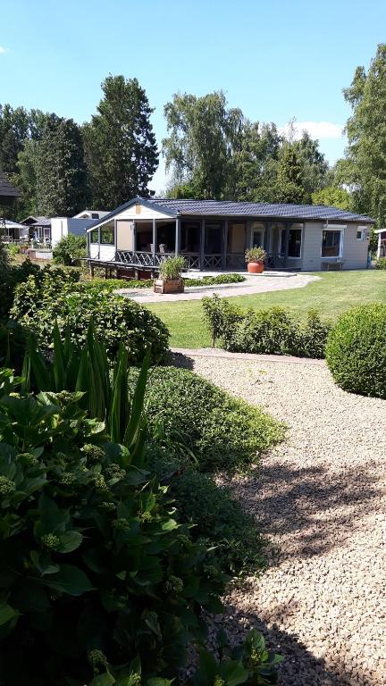 un edificio con un jardín delante de él en Prachtige chalet Wabi Sabi aan het water!, en Geel