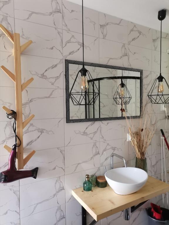 a bathroom with a sink and a mirror at Bieszczadzkie BOHO stodoły z jacuzzi i sauna na wyłączność in Myczkowce