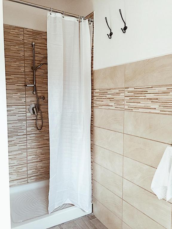 a shower with a white shower curtain in a bathroom at La casetta al maneggio in Catania