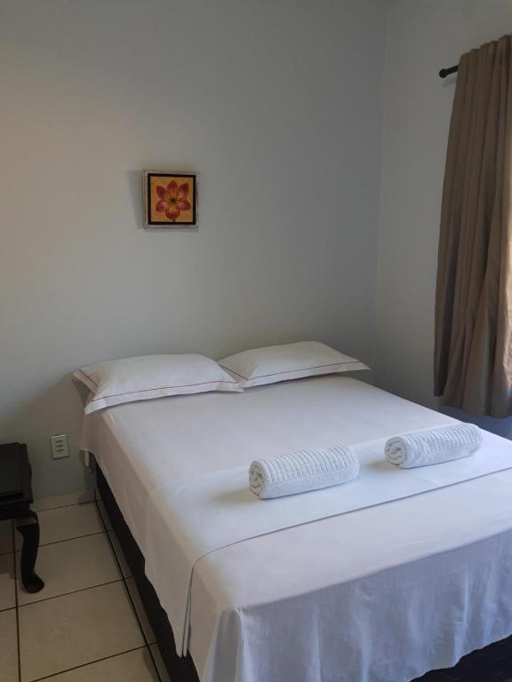 a white bed with two towels on top of it at Pousada Braga in Palmas