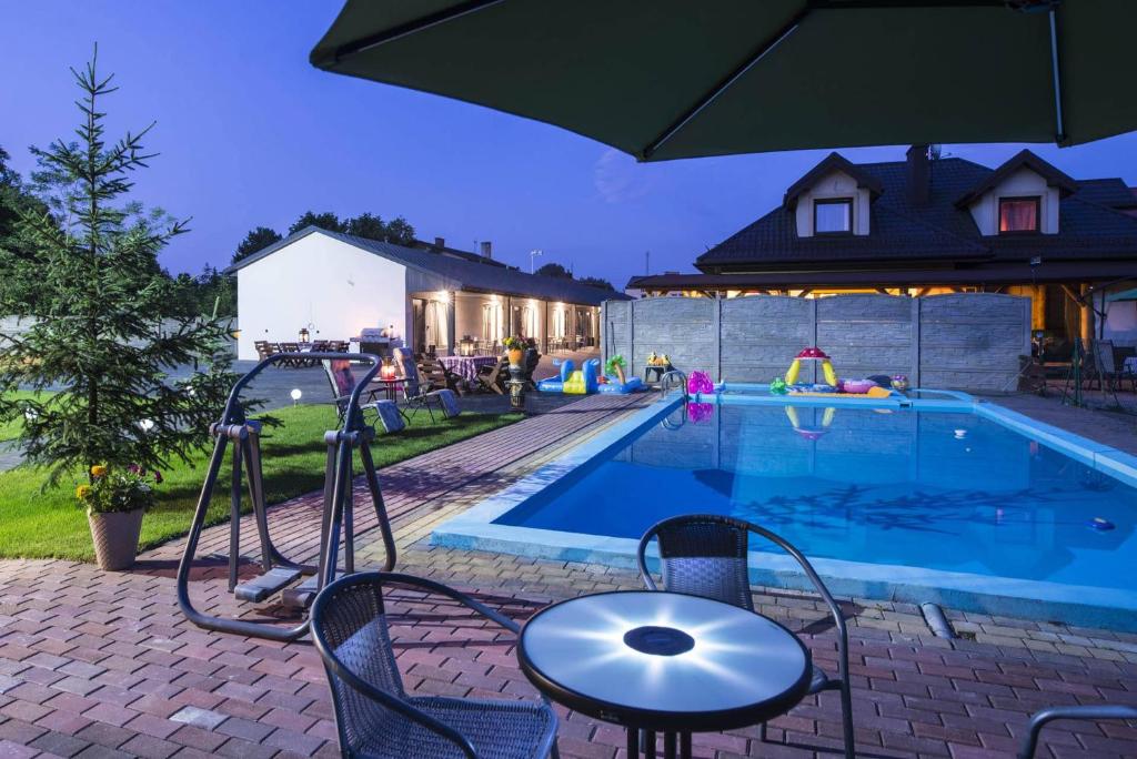 a swimming pool with a table and an umbrella at Jurajskie Apartamenty in Żarki