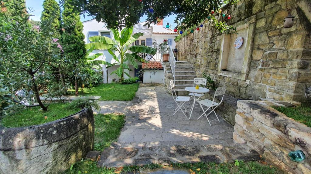 a patio with a table and chairs in a yard at Secret garden of Piran in Piran