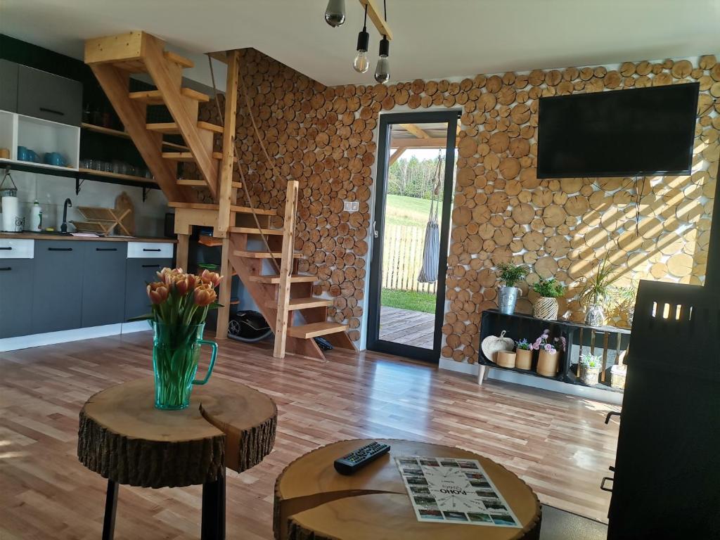 a living room with a table and a tv on a wall at Bieszczadzkie BOHO stodoły z jacuzzi i sauna na wyłączność in Myczkowce