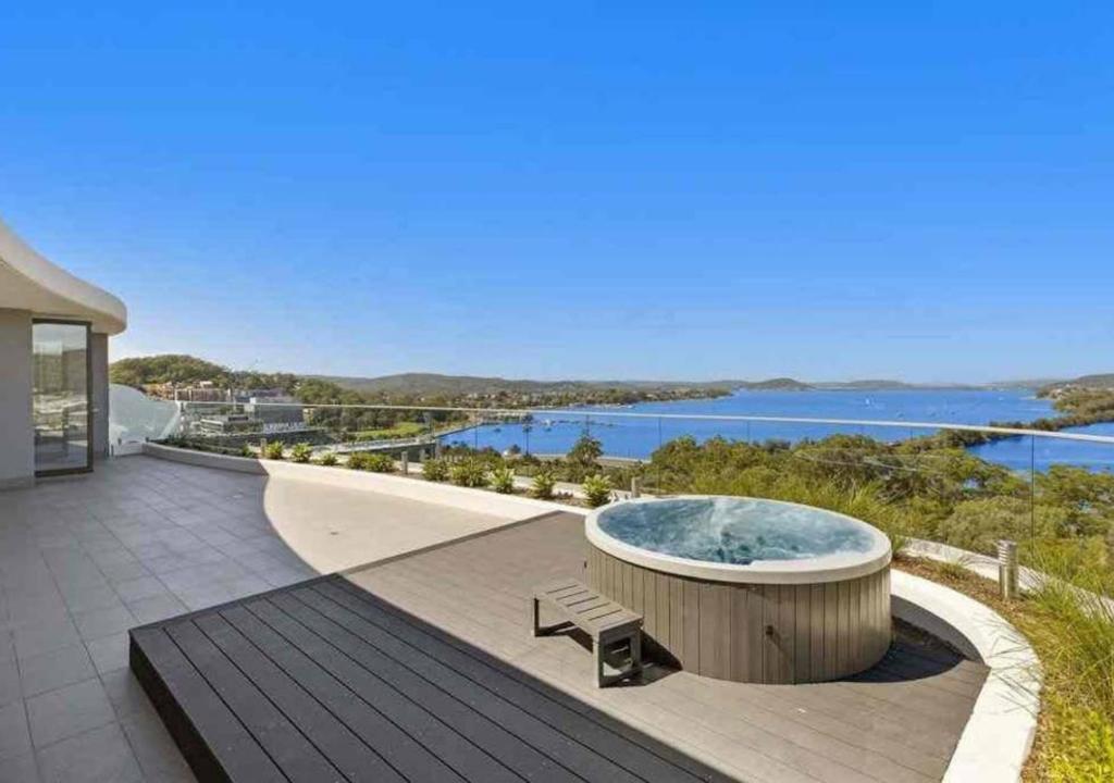 a hot tub on a patio with a view of the water at Stylish Penthouse with Views & Jacuzzi in Gosford