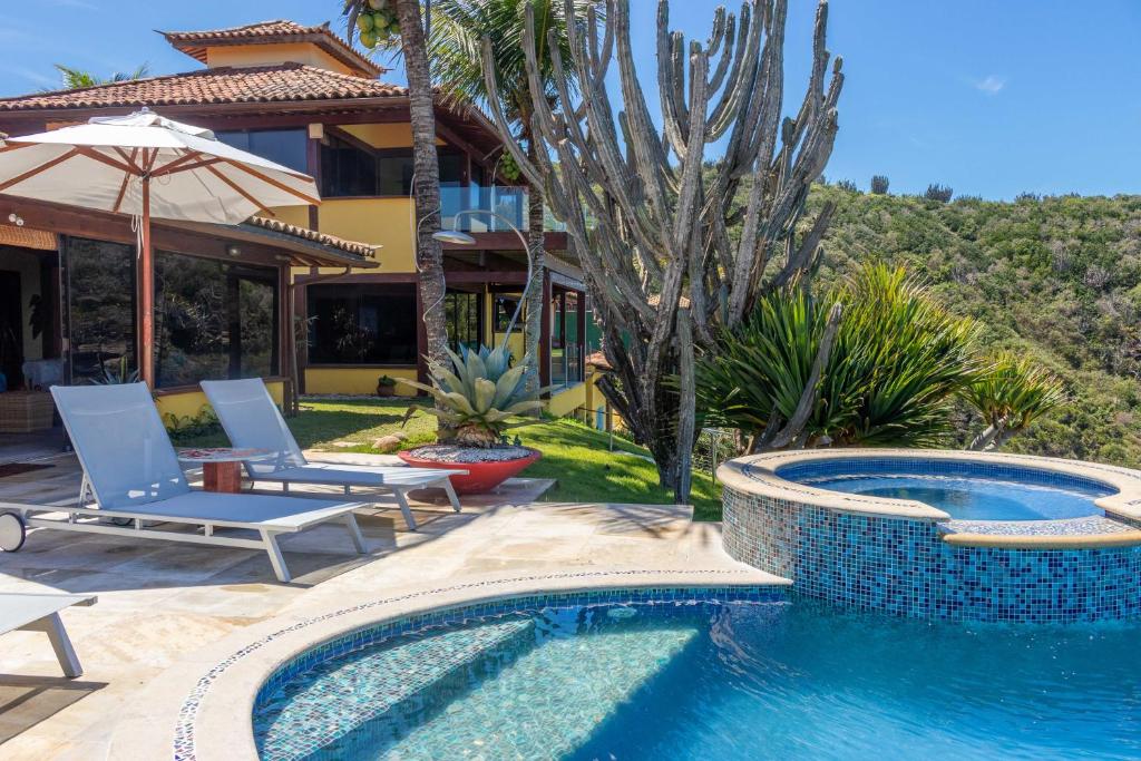 uma piscina com duas cadeiras e uma casa em Cliffside Luxury Inn em Búzios