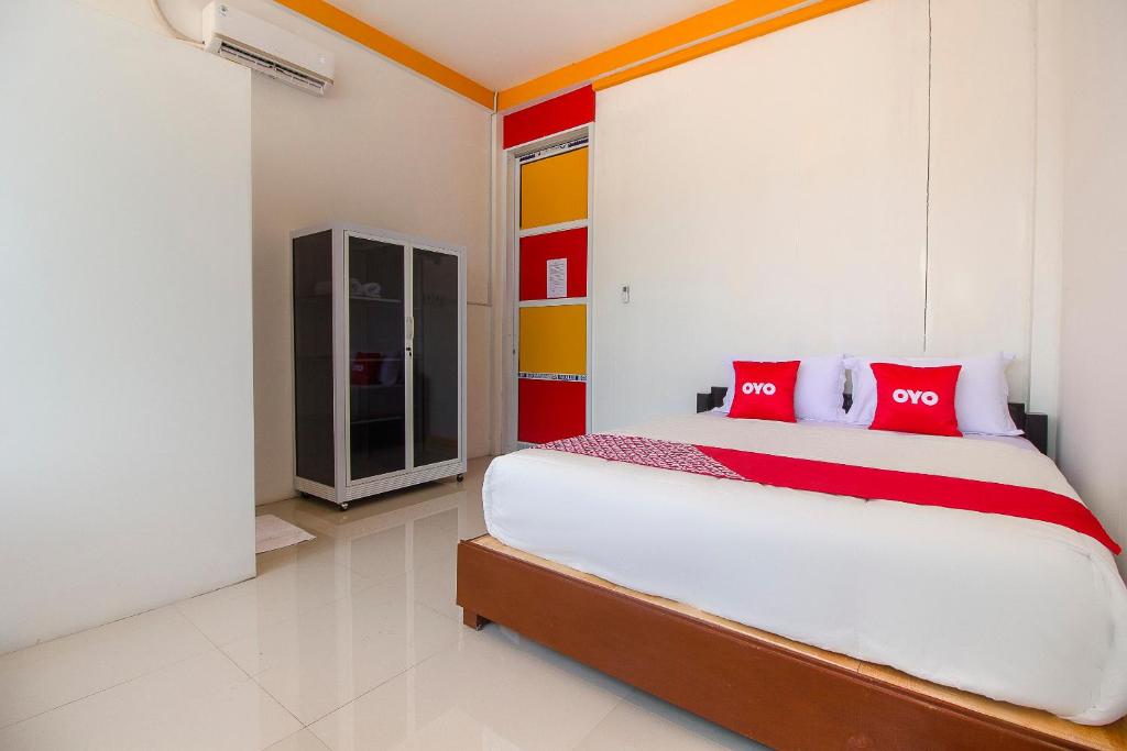 una camera da letto con un grande letto con cuscini rossi di SUPER OYO 3784 Restu Inn a Lampung