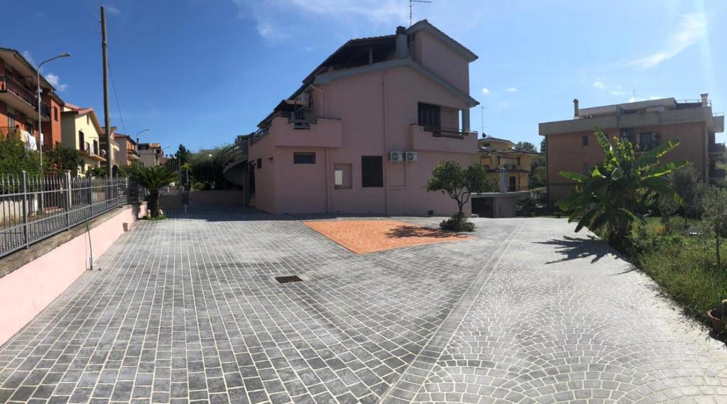 una strada di ciottoli di fronte a un edificio rosa di B&B Antonella a Monterotondo