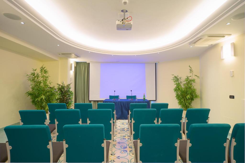a conference room with blue chairs and a projection screen at Le Querce Resort Sea Thermae & Spa in Ischia