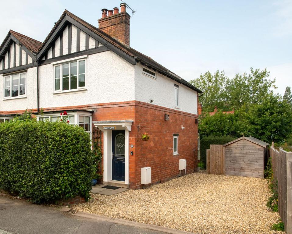 a white and red brick house with a driveway at Magnolia Cottage in Church Stretton