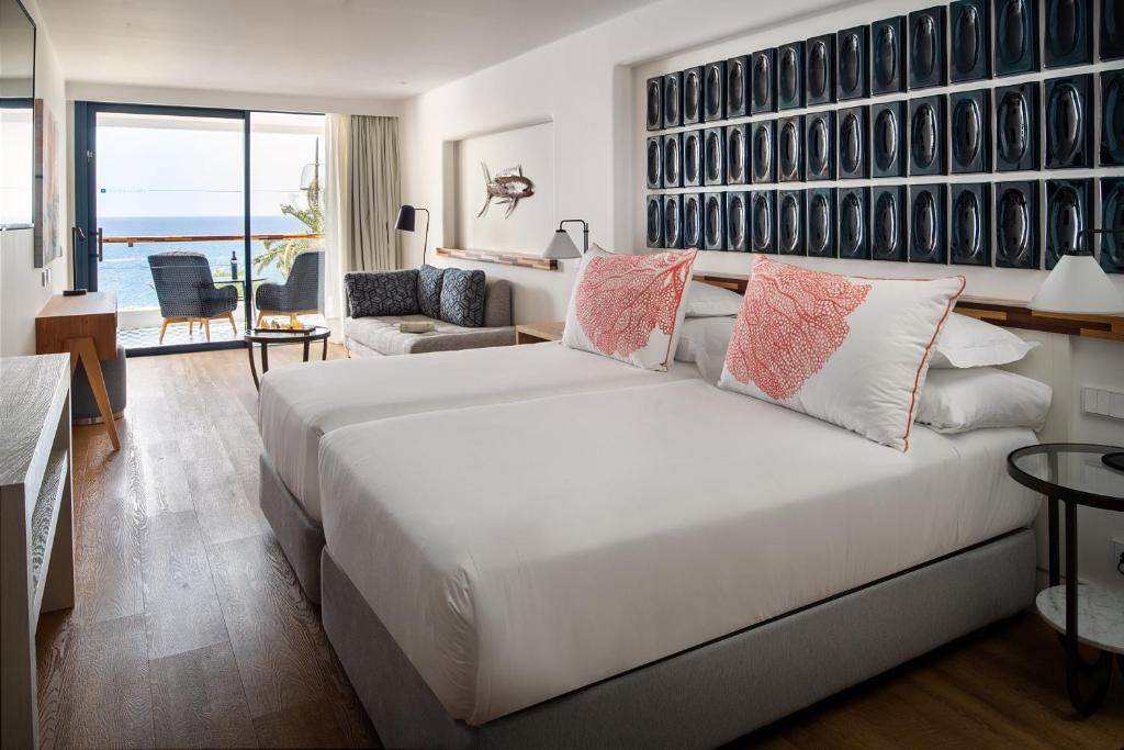 a bedroom with a large white bed and a living room at Hotel Fariones in Puerto del Carmen