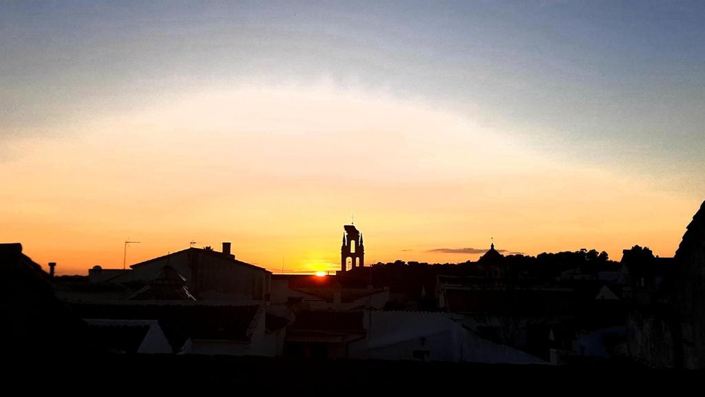 a sunset with a clock tower in a city at Apartamento Callentum (Cazalla de la Sierra) in Cazalla de la Sierra