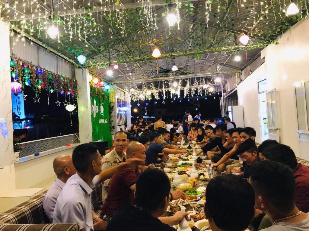 un grupo de personas sentadas en una mesa larga en Khách Sạn Nhà Hàng Lương Gia en Ha Giang