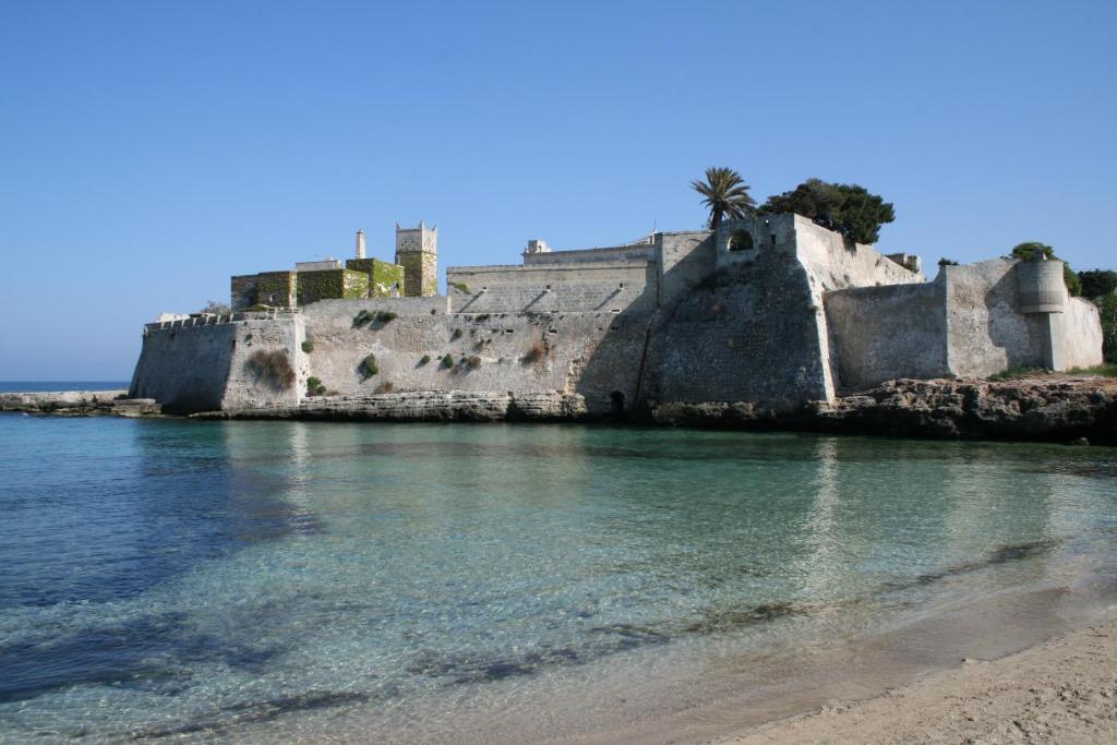 a castle on the beach next to the water at B&B Al Picchio in Monopoli