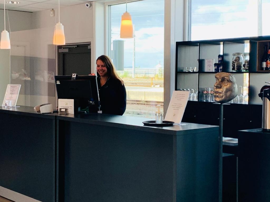 a woman standing behind a counter with a laptop at P-Hotels Brattøra in Trondheim