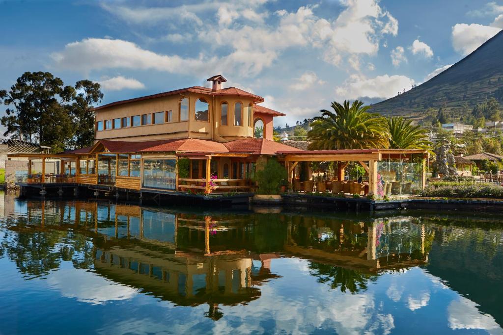a building sitting on top of a body of water at Hosteria Cabañas Del Lago in Otavalo