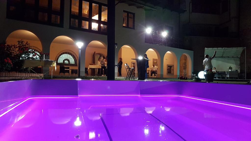 a pool with pink lighting in front of a building at Hotel Locanda San Giacomo in Agliano Terme