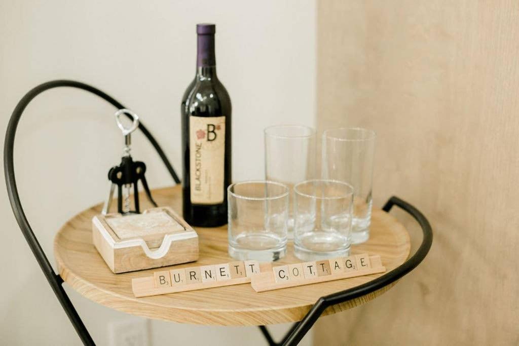 a table with a bottle of wine and glasses on it at Burnett Cottage - Pine in Cedar Rapids
