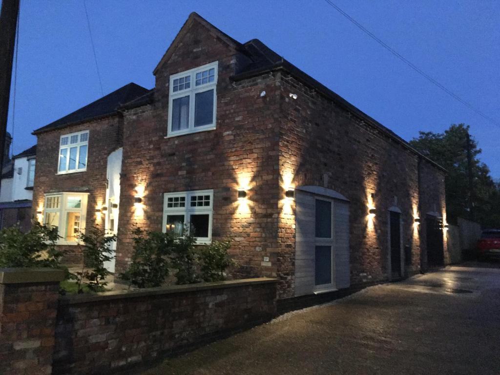 un edificio de ladrillo con luces en el lateral. en The Old Coach House en Polesworth